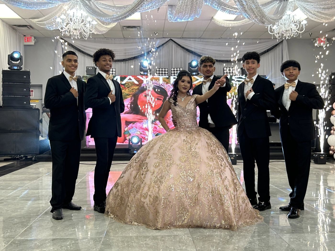 Quinceañera in a gold gown surrounded by her cadets